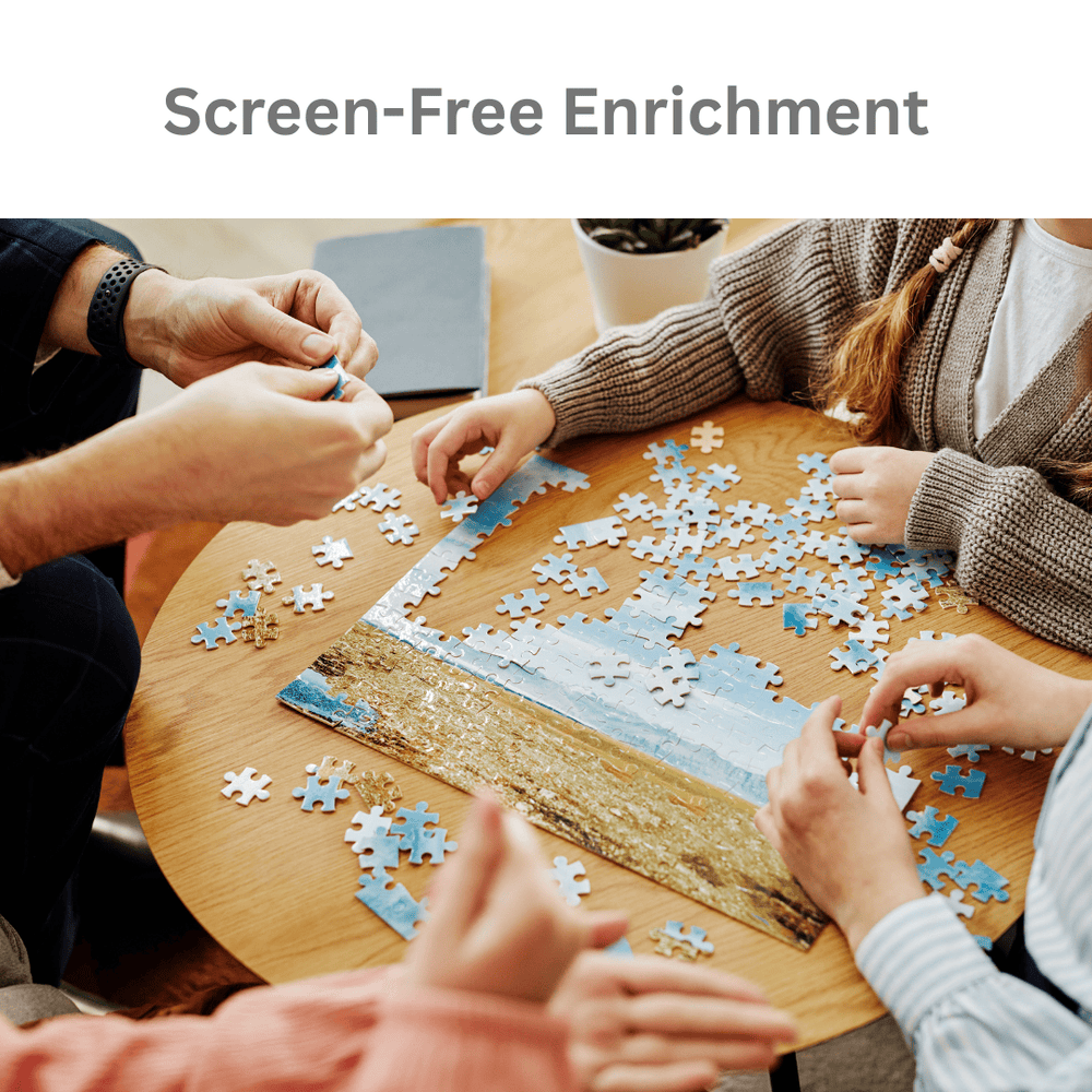 A group of people sitting around a wooden table assembling a jigsaw puzzle of a beach scene. The image includes the text 'Screen-Free Enrichment' at the top, indicating an educational or family activity product.