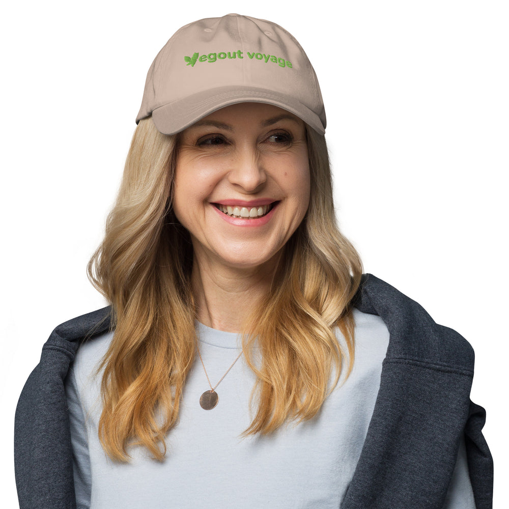 Woman wearing a beige cap with 'vegout voyage' logo on a white background