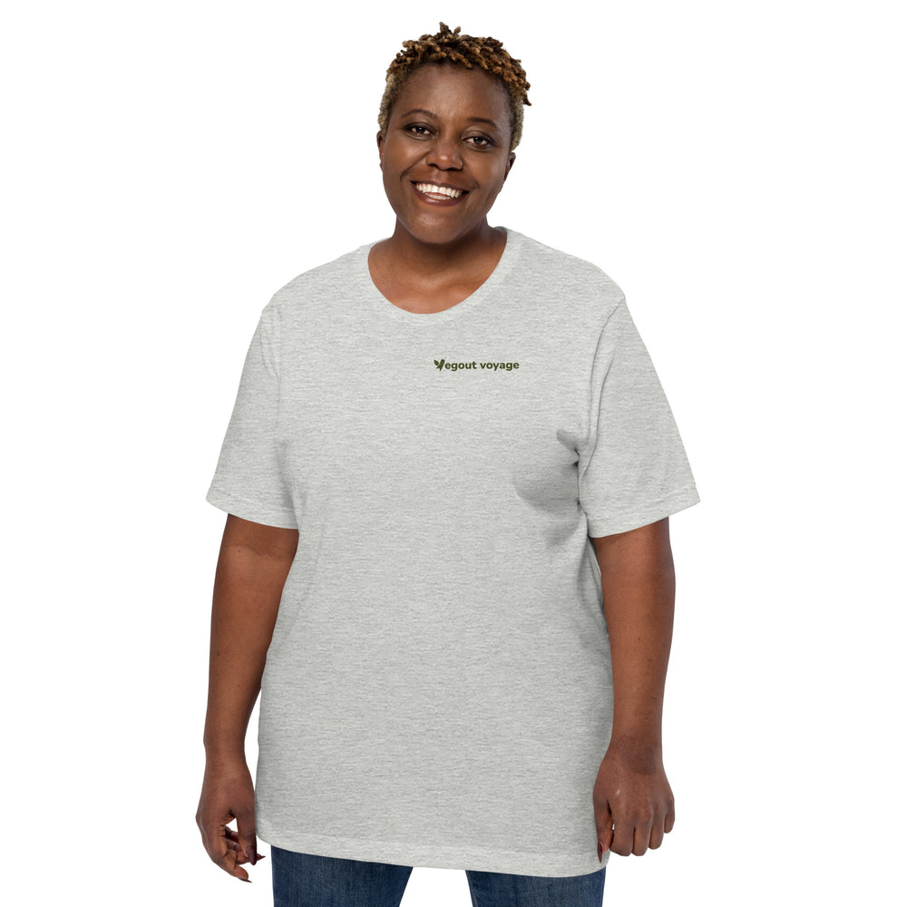 Smiling woman wearing a light heather gray "Vegout Voyage" t-shirt, posing against a white background.